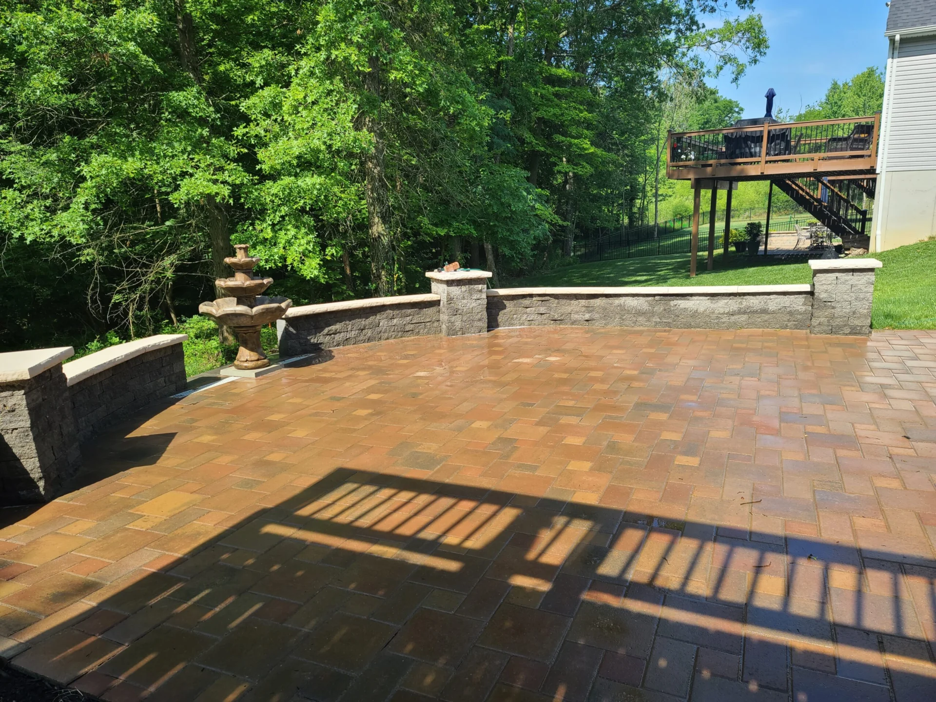 Sunlit paver patio with railing and built-in lighting in a Cincinnati, Ohio backyard